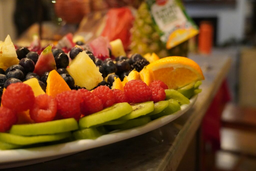 Various fruit arranged elegantly on a white plate with a blurred background of a kitchen